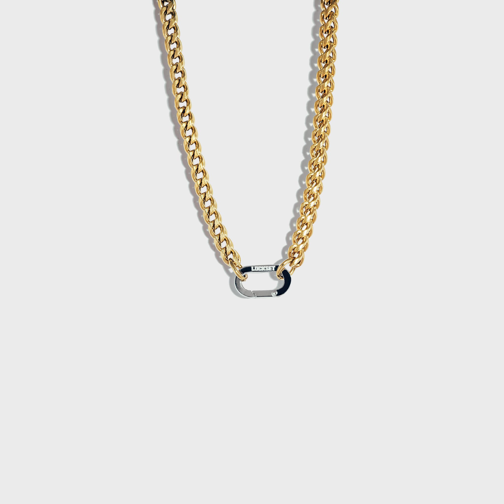 Thick gold chain with silver carabiner clasp on white background