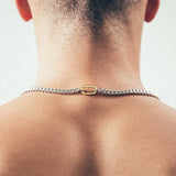 Close-up of man wearing silver chain necklace with gold carabiner clasp 