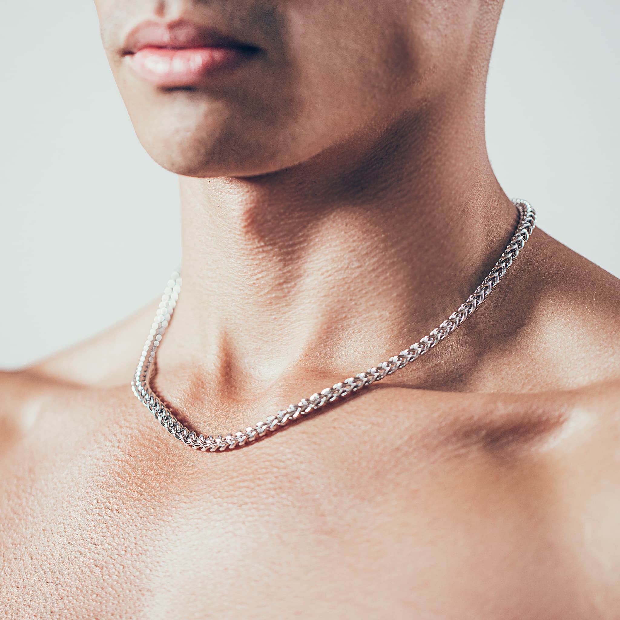 Close-up of man wearing silver chain necklace 