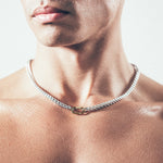 Close-up of man wearing silver chain necklace with gold carabiner clasp 