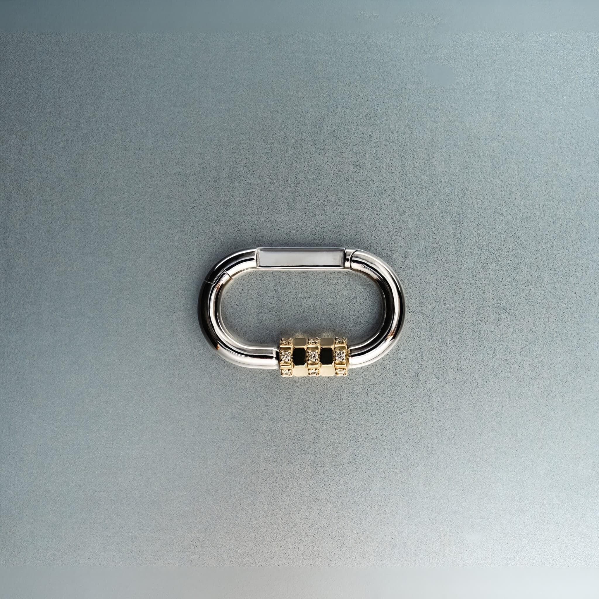 Silver carabiner pendant featuring gold lock with diamond details on gray background