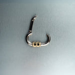 Open silver carabiner pendant featuring gold lock with diamond details on gray background