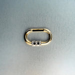 Gold carabiner pendant with diamond-detail lock on light gray background