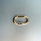 Gold carabiner pendant with diamond-detail lock on light gray background