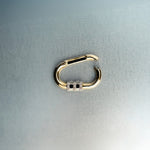 Open gold carabiner pendant featuring diamond lock detail on light gray background