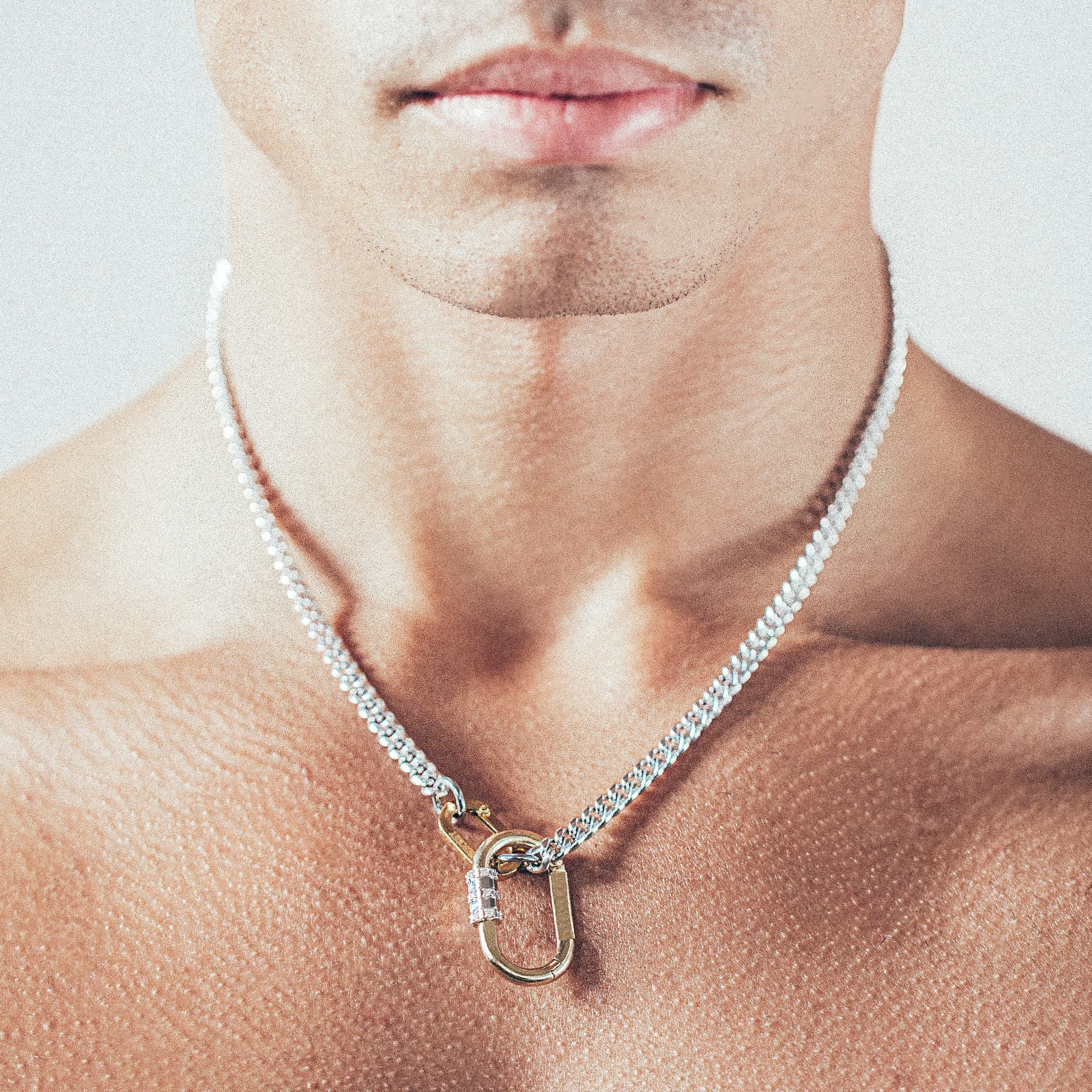 Close-up of man wearing silver chain necklace with gold carabiner lock pendant and gold carabiner clasp