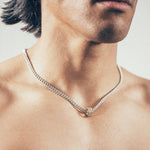Close-up of person wearing silver chain necklace with gold hex nut bead covered in white diamonds