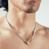 Close-up of person wearing silver chain necklace with gold hex nut bead covered in white diamonds and gold carabiner clasp. 