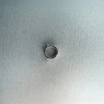 Silver hex nut bead with black diamond detailing on light gray surface