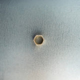 Gold hex nut bead with diamond detailing on light gray surface