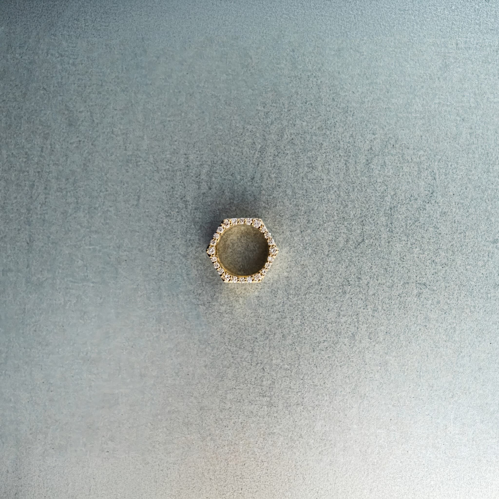 Gold hex nut bead with diamond detailing on light gray surface