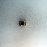 Gold hex nut bead with diamond detailing on light gray surface