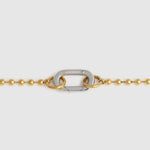 A close-up of a gold ball chain necklace featuring a central silver carabiner clasp with the brand name 'LOCKSET' engraved on it, set against a light gray background.