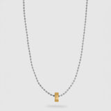 A delicate silver ball chain necklace featuring a small, polished gold hexagonal pendant at the center, displayed against a light gray background.