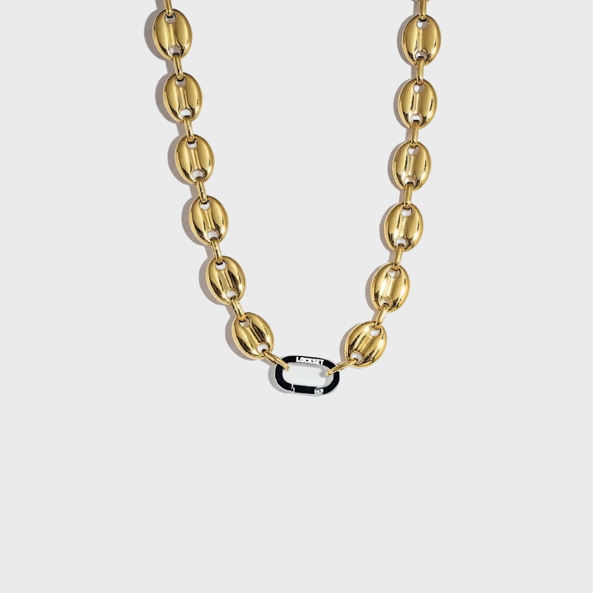 Gold mariner-link chain with silver carabiner clasp on white background