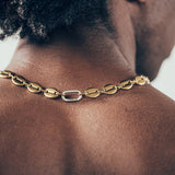 Close-up of man wearing gold mariner chain necklace with silver carabiner clasp 