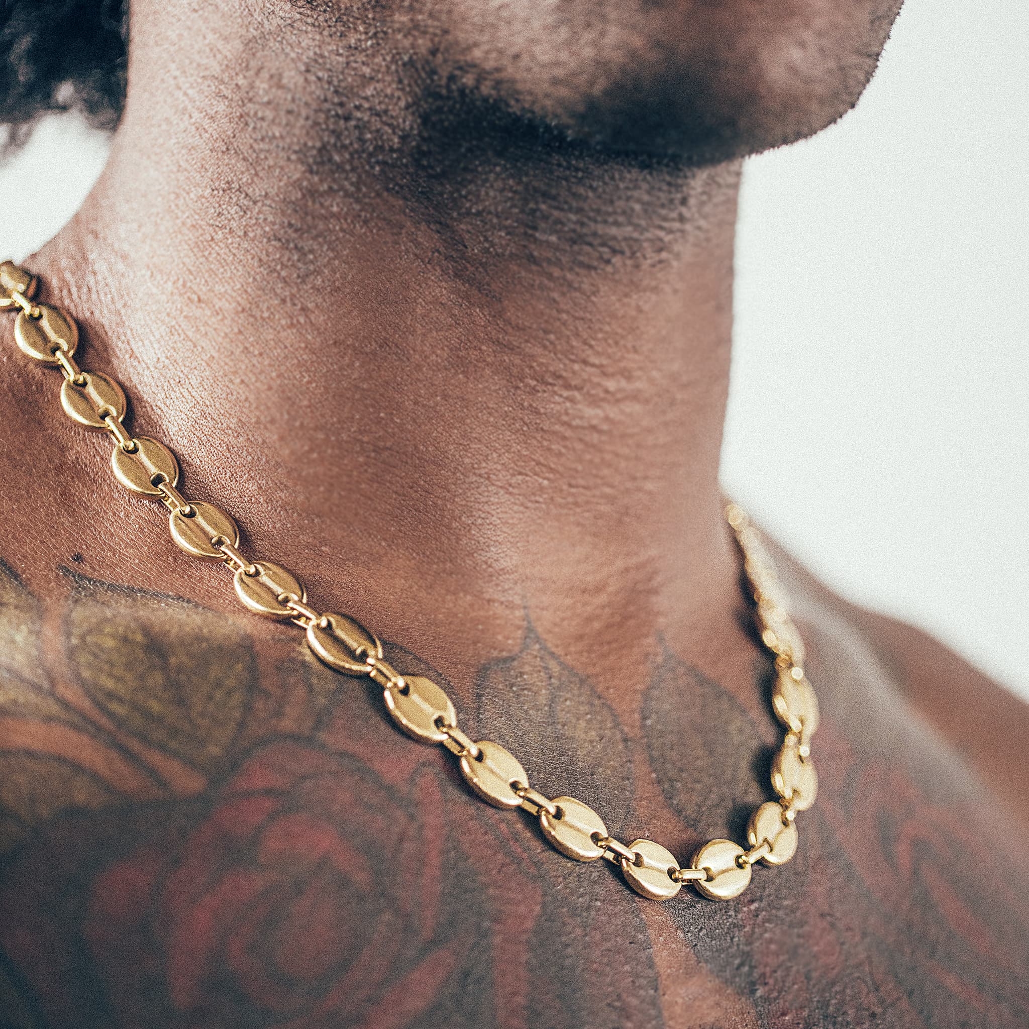 Close-up of man wearing gold mariner chain necklace