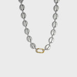 Silver mariner-link chain with gold carabiner clasp on white background
