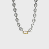 Silver mariner-link chain with gold carabiner clasp on white background