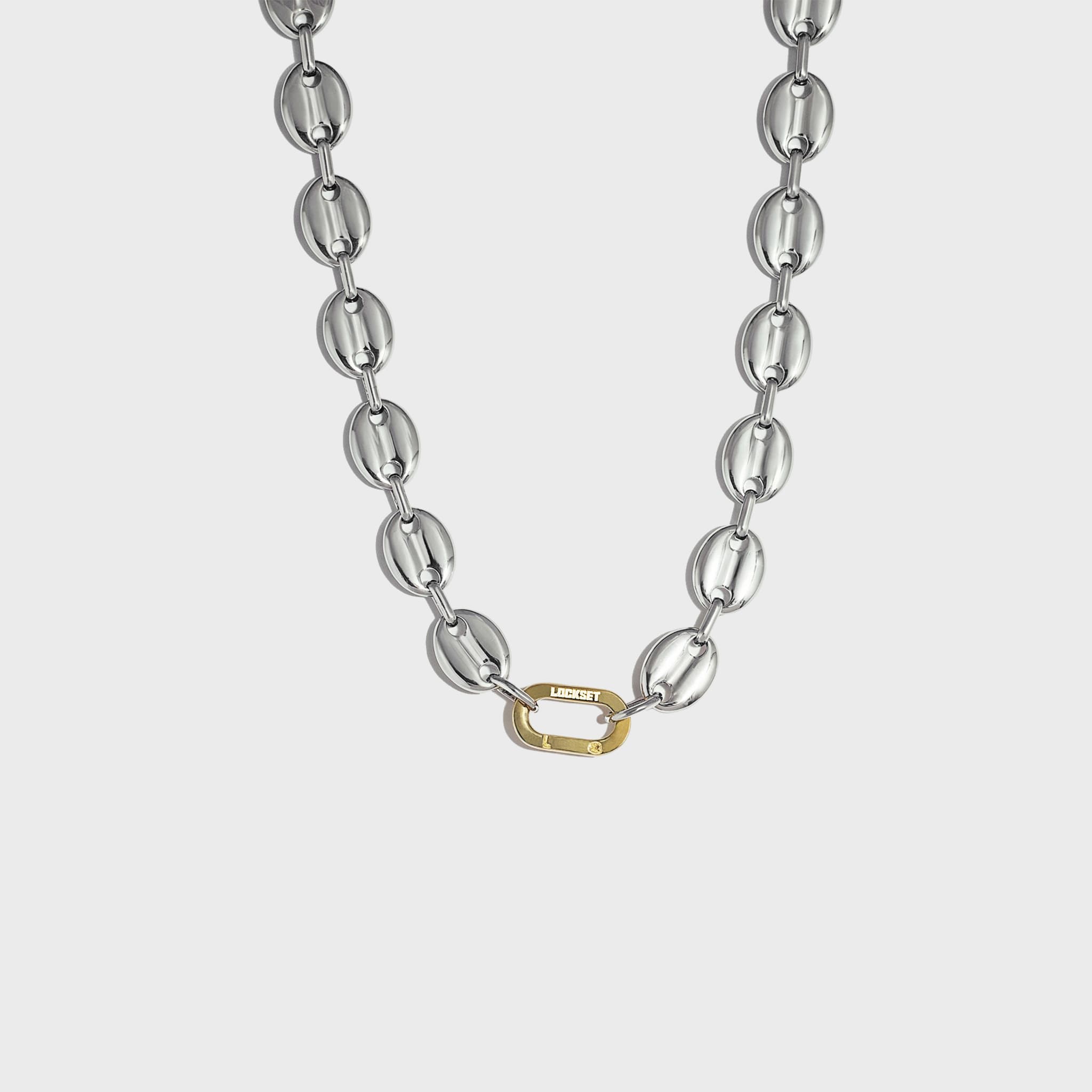 Silver mariner-link chain with gold carabiner clasp on white background