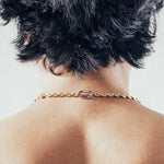 Close-up of man wearing gold mariner chain necklace with silver carabiner clasp