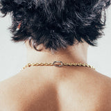 Close-up of man wearing gold mariner chain necklace with silver carabiner clasp