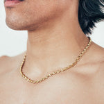Close-up of man wearing gold mariner chain necklace