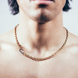 Close-up of man wearing gold mariner chain necklace with silver carabiner clasp