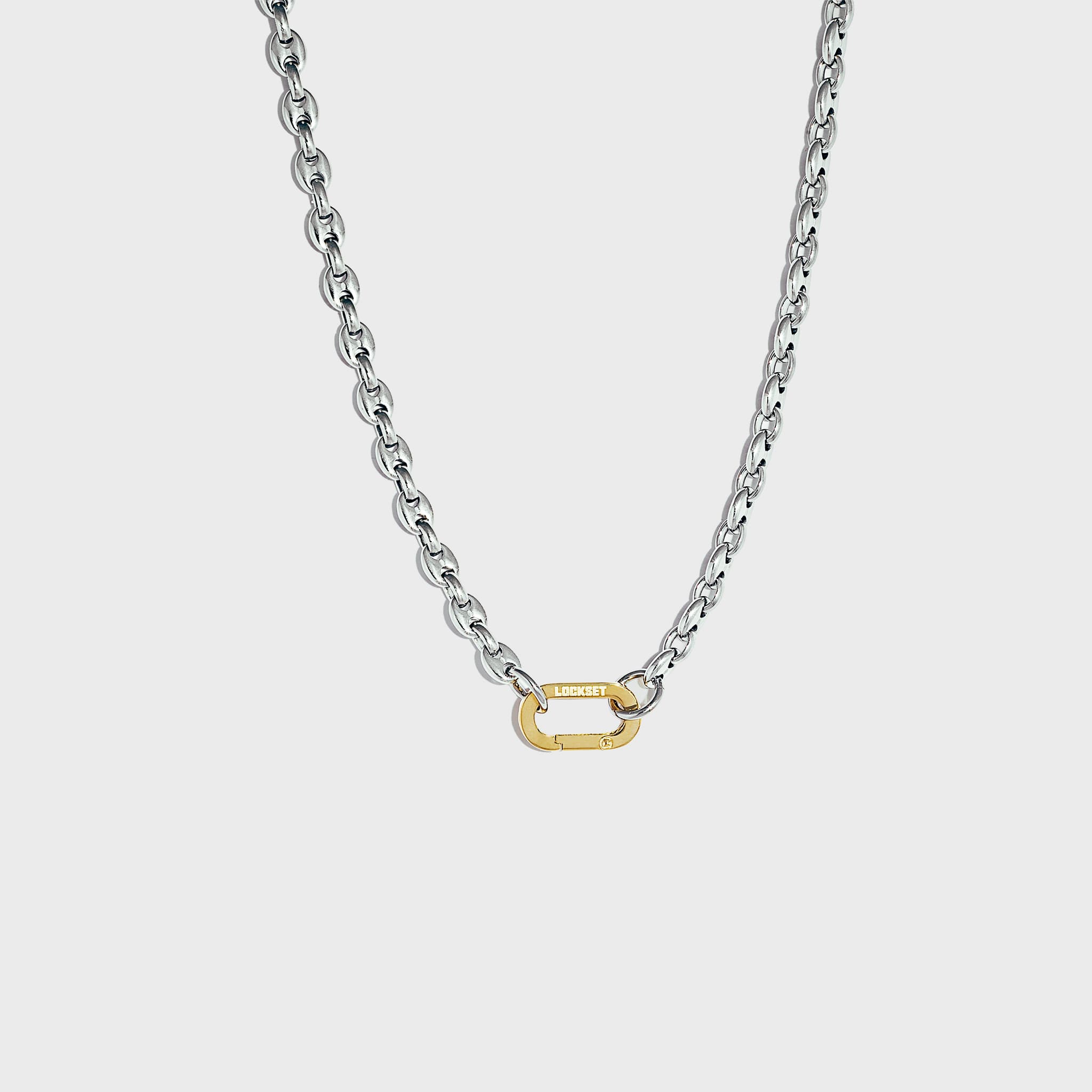Silver mariner-link chain with gold carabiner clasp on white background