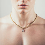 Man wearing gold chain necklace with rectangular six-sided silver tag pendant 