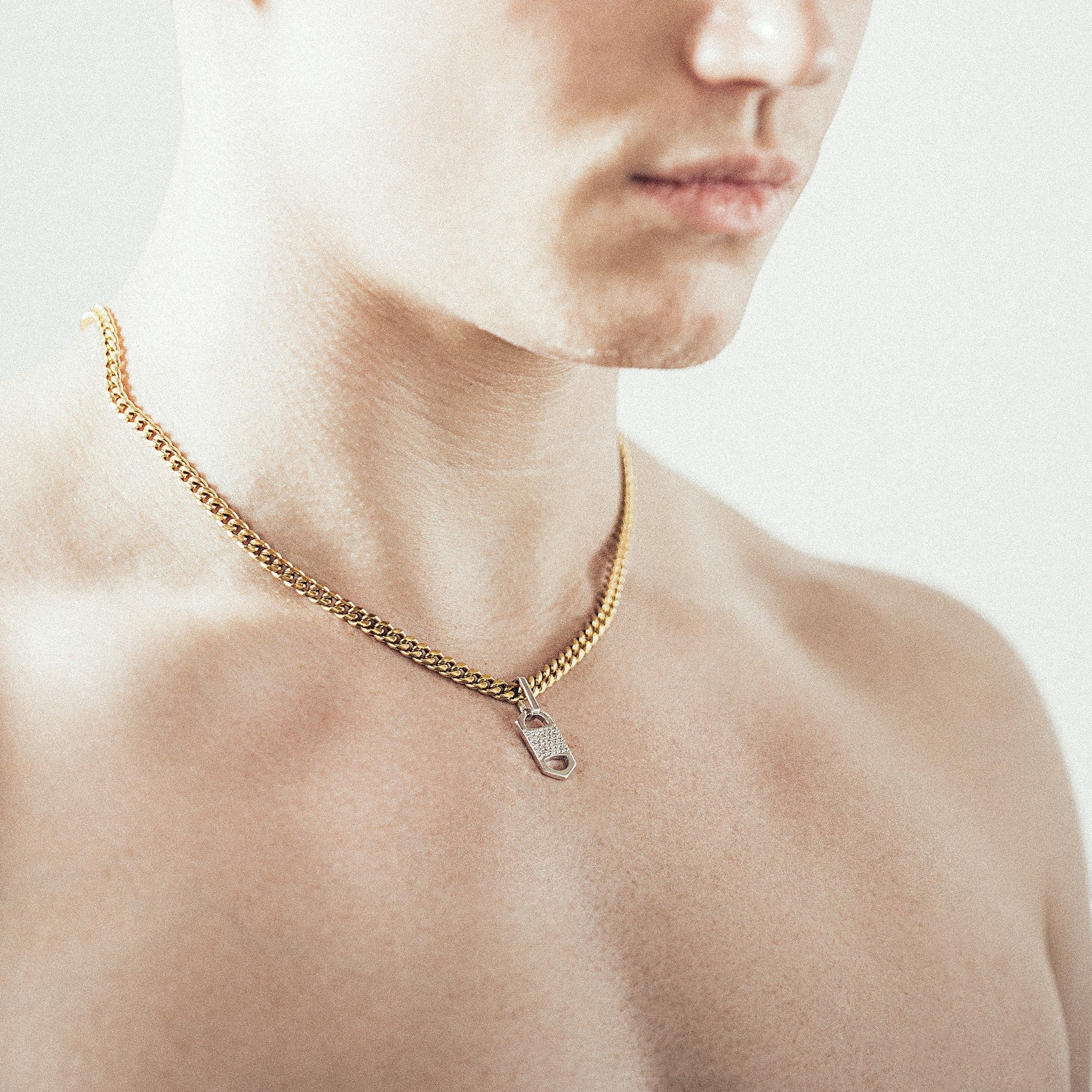Man wearing gold chain necklace with rectangular six-sided silver tag pendant 