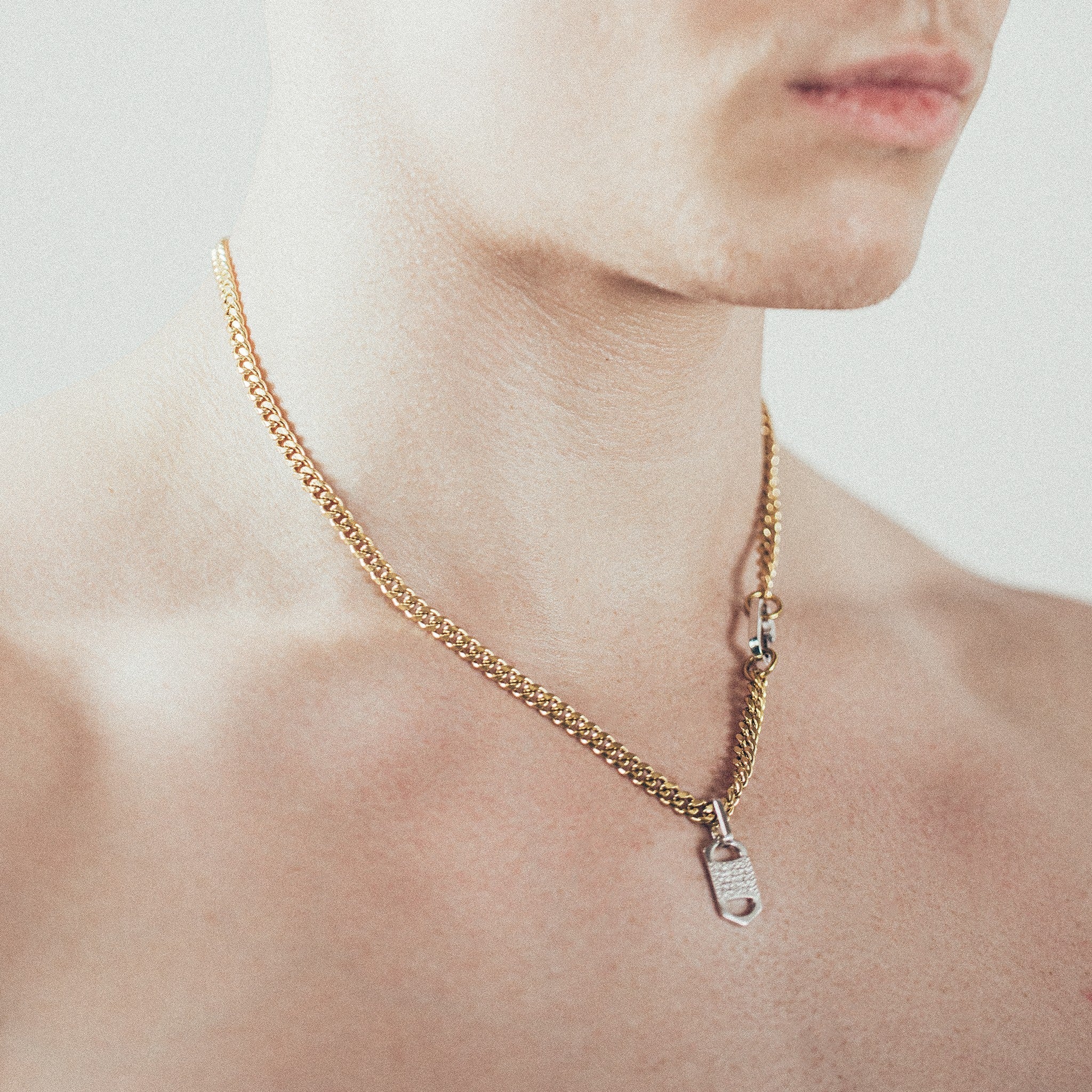 Man wearing gold chain necklace with rectangular six-sided silver tag pendant   and silver carabiner clasp