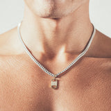 Man wearing silver chain necklace with rectangular six-sided gold tag pendant 