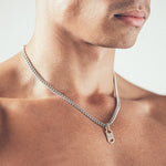 Man wearing silver chain necklace with geometric gold tag pendant - side view