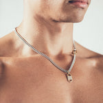 Man wearing silver chain necklace with geometric gold tag pendant and carabiner clasp