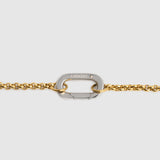 A close-up of a gold chain bracelet featuring a silver-toned carabiner clasp engraved with the brand name 'LOCKSET' on a light gray background.