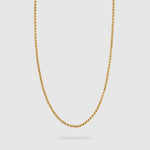 A delicate gold chain necklace with a small, polished rolo link design, suspended against a light gray background.