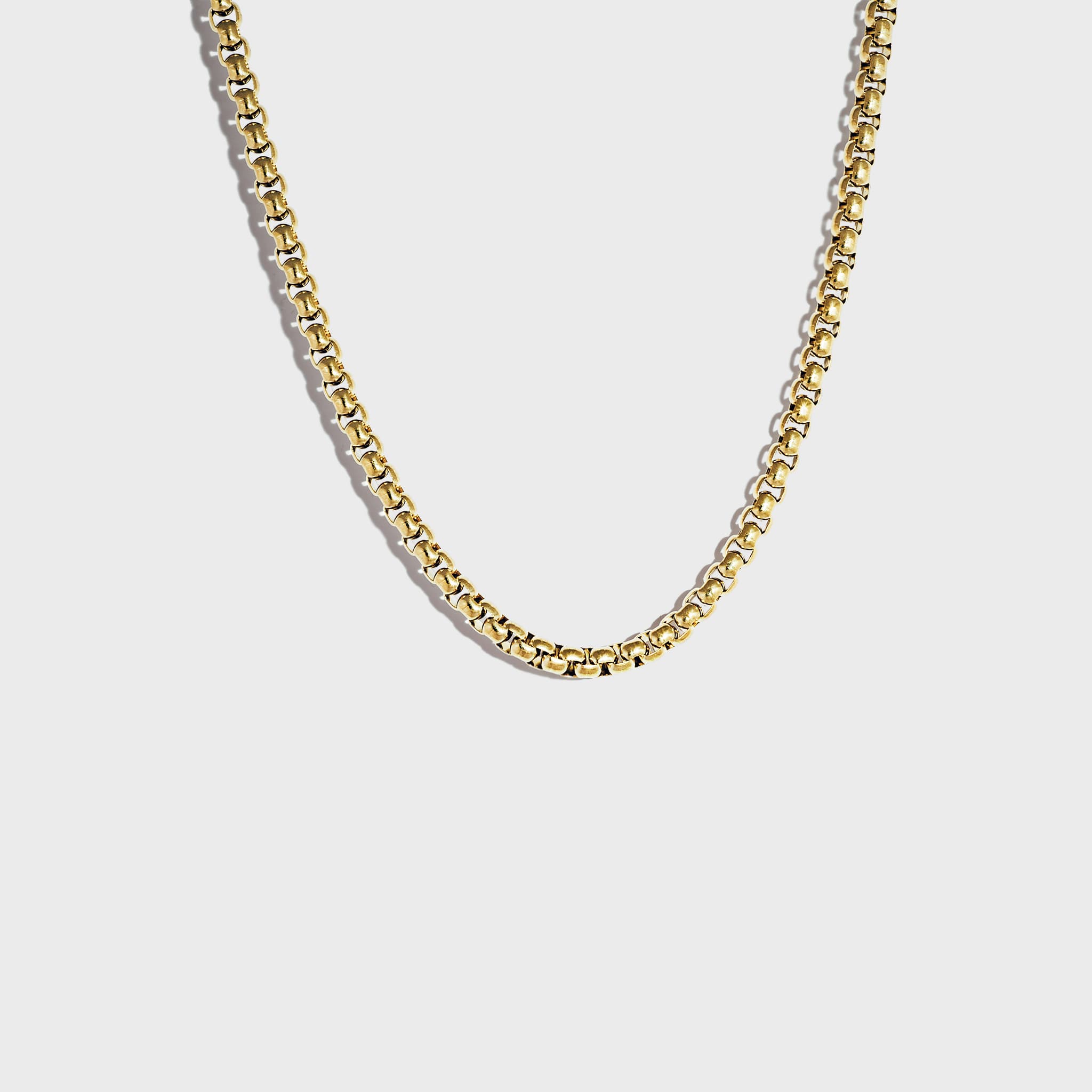 Thick gold rolo chain necklace on white background