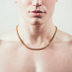 Close-up of man wearing thick gold rolo chain necklace”