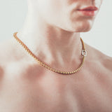 Close-up of man wearing thick gold rolo chain necklace with silver carabiner clasp