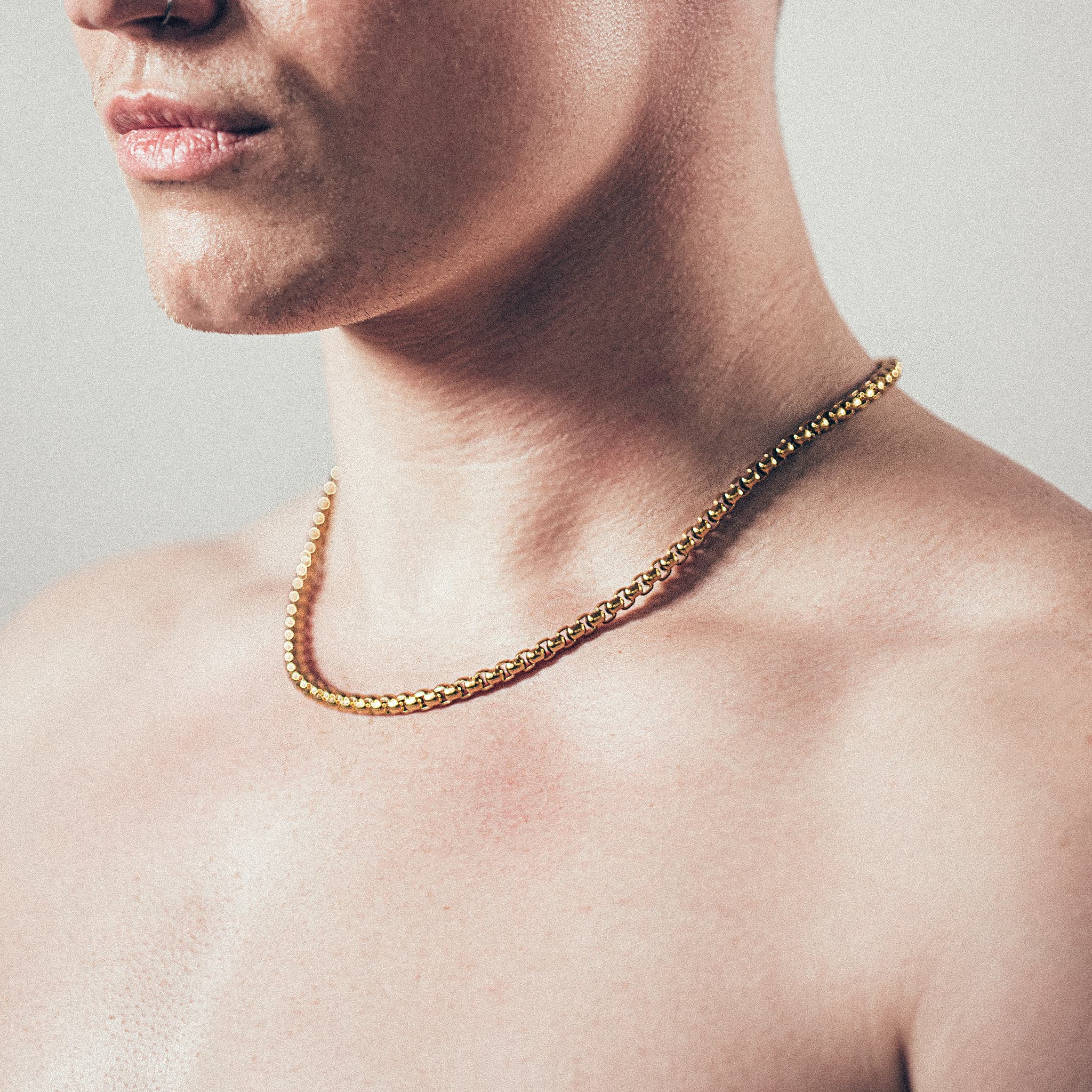 Close-up of man wearing thick gold rolo chain necklace”