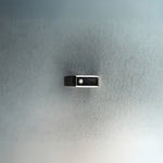 Black and silver rectangular signet-style ring with diamond detail on textured gray background