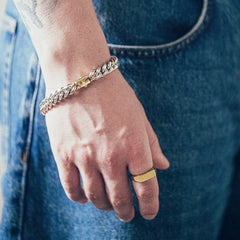 Close-up of hand wearing silver bracelet and rectangular gold signet ring on textured fabric background
