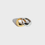 Gold and silver round signet rings stacked on white background