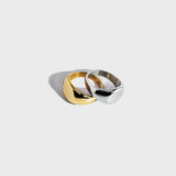 Gold and silver round signet rings stacked on white background