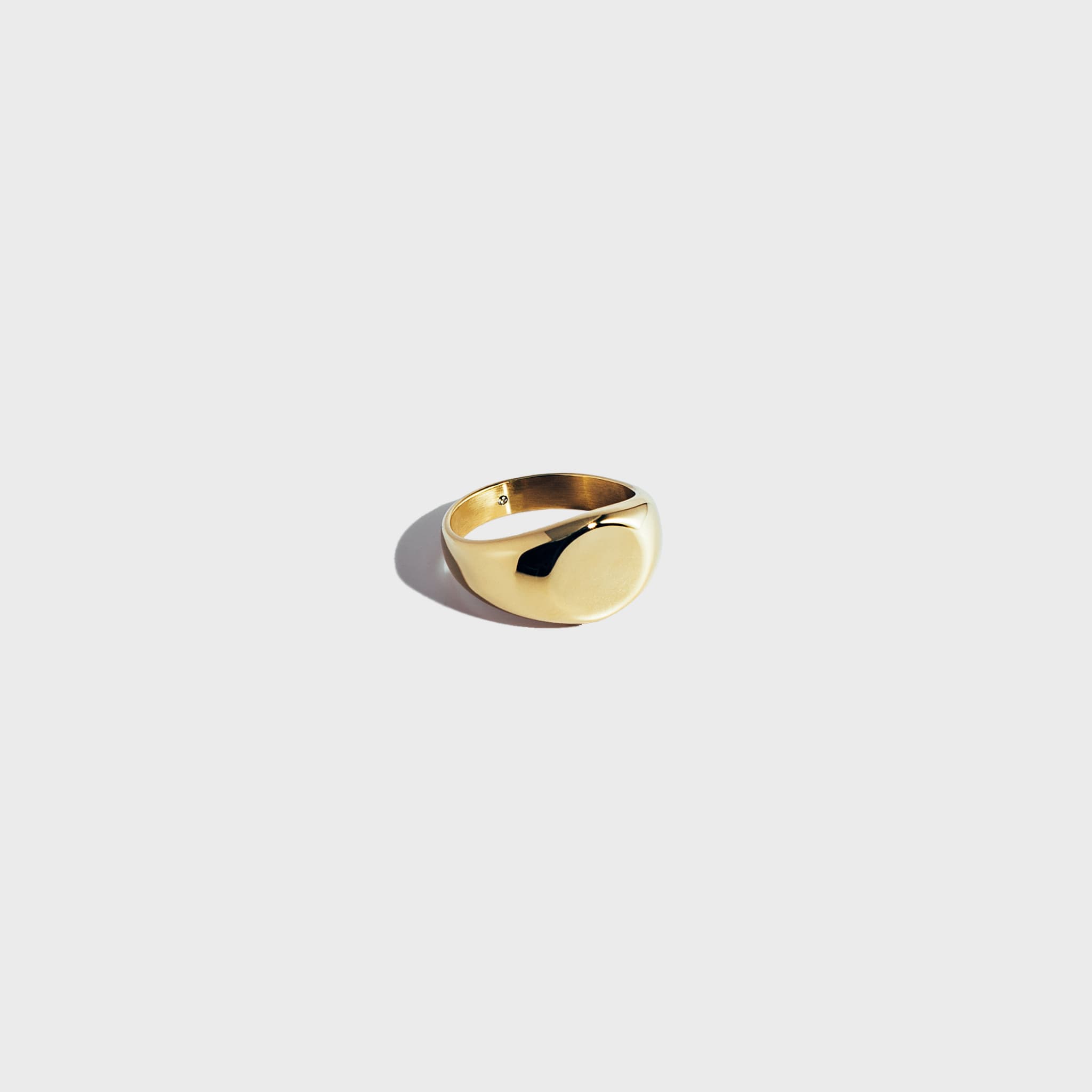 Gold circular signet ring on white background
