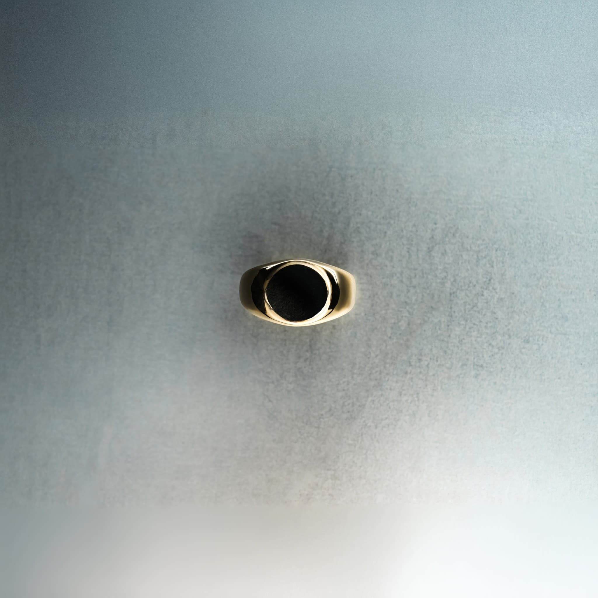 Gold ring with round signet top on light gray background